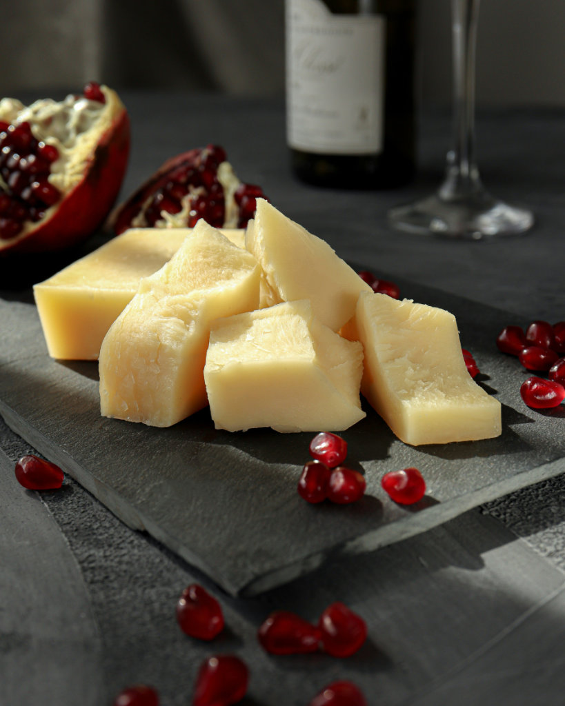 Parmesean cheese and pomegrante on a cutting board.