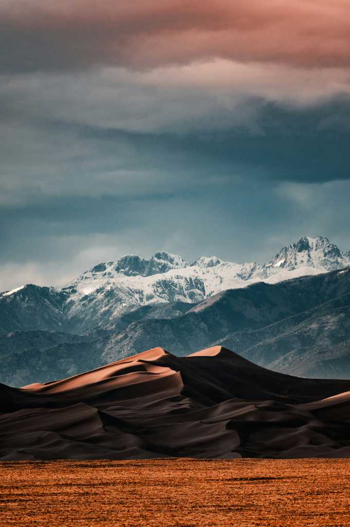 A small red mountain in front of a bigger mountain.